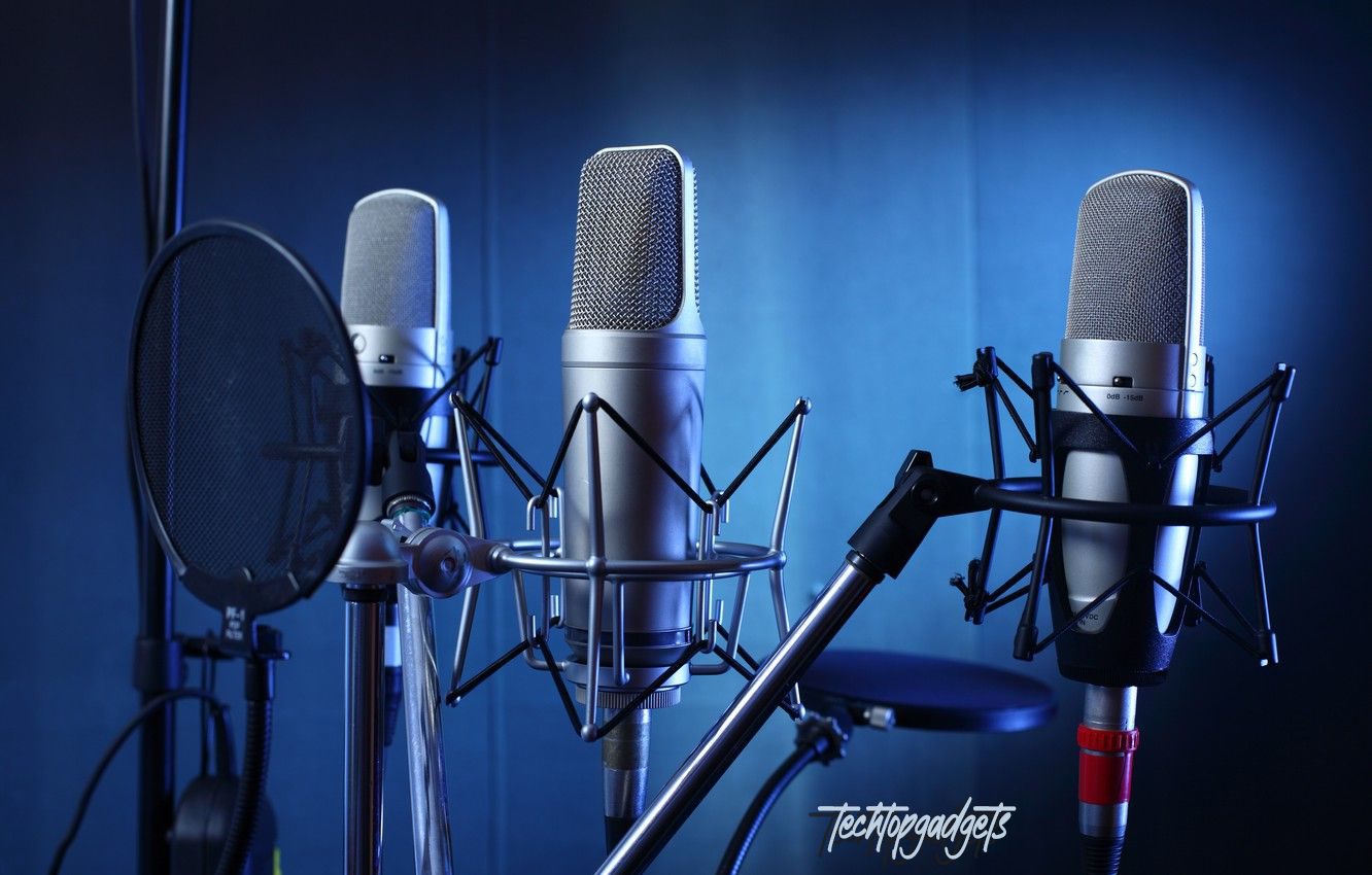 A professional studio setting showcasing three of the best microphones of 2024, each mounted on a sleek stand with shock mounts and pop filters, against a moody blue backdrop, highlighting the cutting-edge design and technology for superior audio capture.