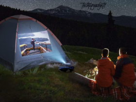 Two campers enjoy a serene night under the stars, with a portable projector displaying a vivid image on their tent. This setup exemplifies the best portable projector for camping, creating an unforgettable outdoor theater experience.