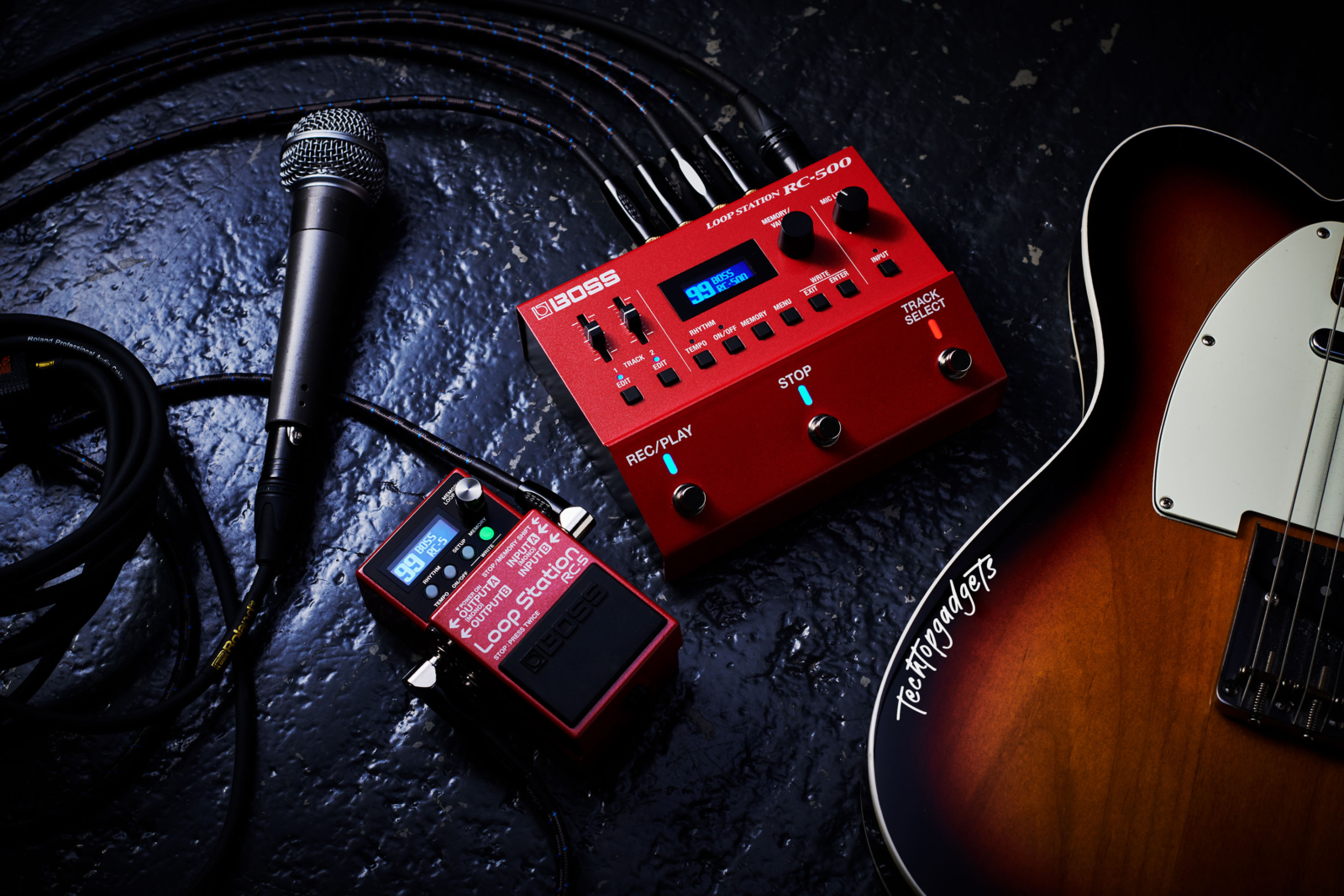 A setup view of the Boss RC-500 best looping pedal alongside a guitar and microphone, illustrating how it integrates into a musician's live or studio setup.