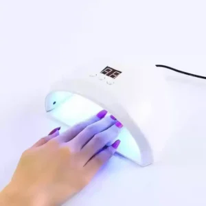 A person's hand under a white UV nail dryer with a digital display, illustrating the process of achieving professional salon-quality nails at home.