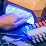 A person uses a digital nail art printer, with their hand under a UV light to cure the polish, showcasing the integration of technology in beauty routines and the importance of researching potential health implications like cancer risks associated with UV exposure.