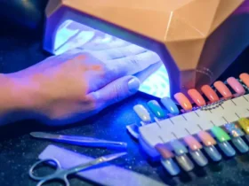 A person uses a digital nail art printer, with their hand under a UV light to cure the polish, showcasing the integration of technology in beauty routines and the importance of researching potential health implications like cancer risks associated with UV exposure.