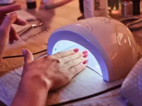 Ambient setting with a hand being placed under a UV nail dryer, emphasizing the convenience and effectiveness of home nail artistry with the aid of UV technology.